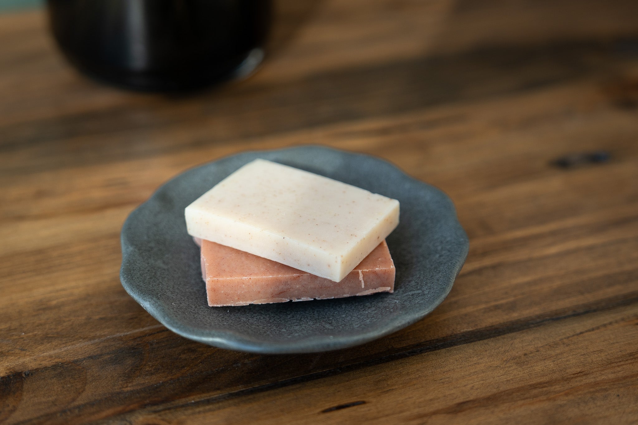 2 bars from the crooked chimney farm soap medley gift box on a small black plate.