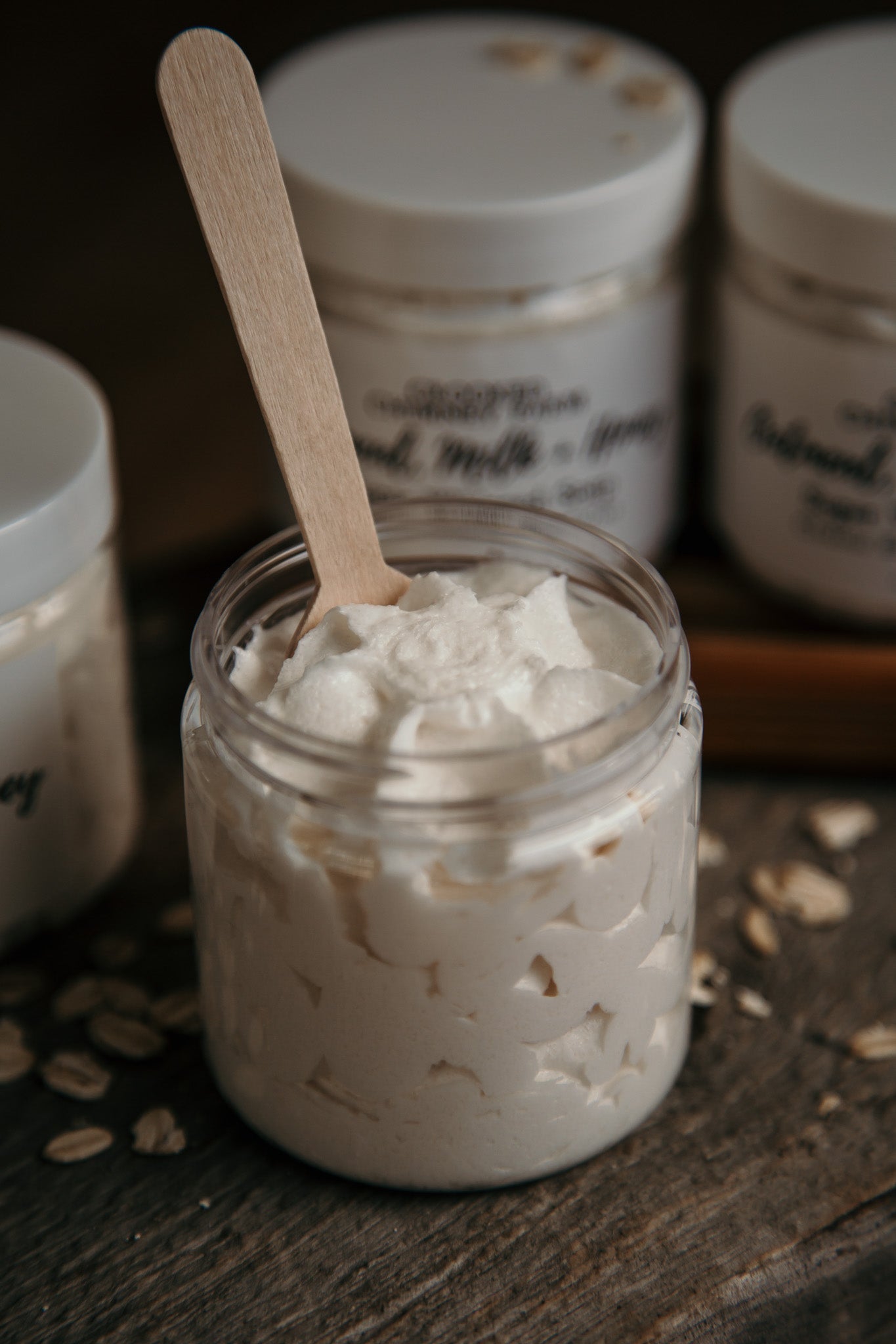 oatmeal milk and honey sugar whipped soap, open jar with wood spoon in it.