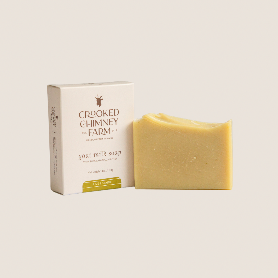 a bar of lime and ginger goat milk soap next to soap box, beige background