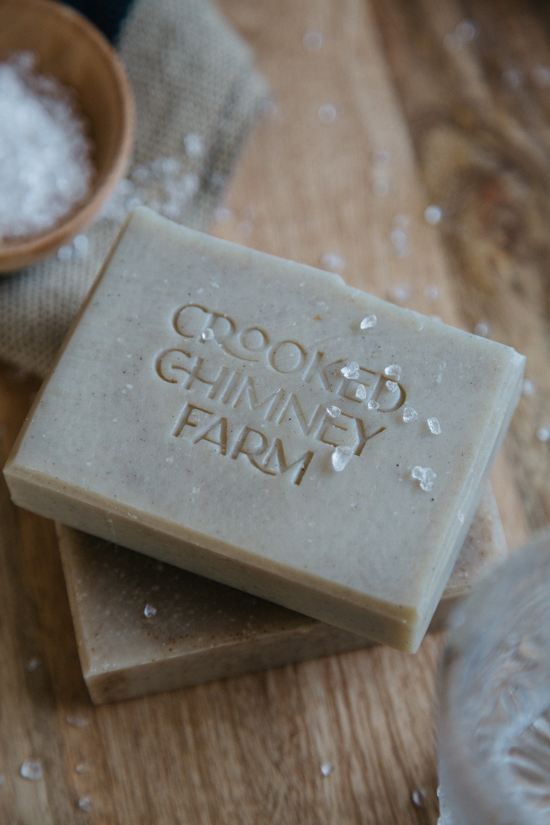 Drift and Tide soap bars stacked on a wood platter with sea salt sprinkled around