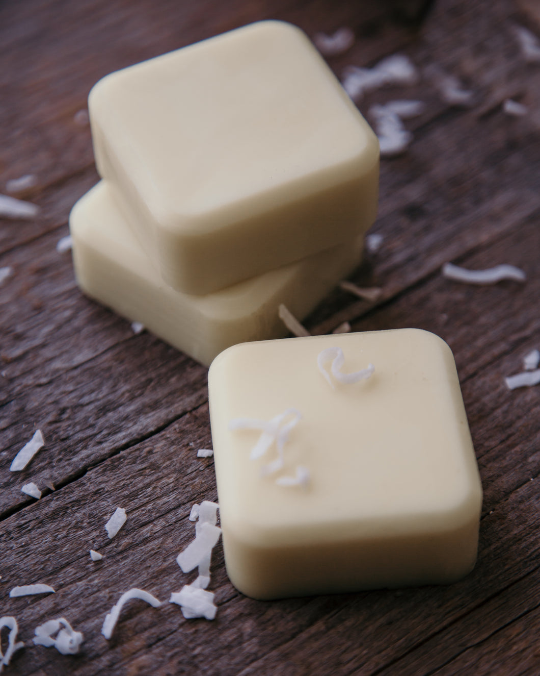 Three coconut lotion bars surrounded by shredded coconut.