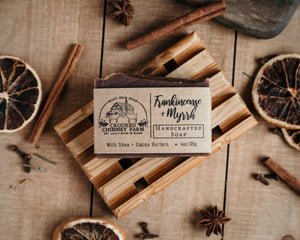 Frankincense and myrrh goat milk soap with brown kraft label on wood soap deck