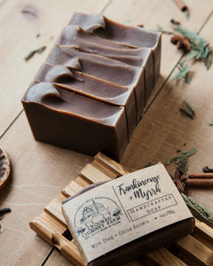 frankincense and myrrh goat milk soap 5 bars lined up, one bar on soap dish with label. 