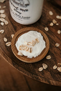 oatmeal milk honey lotion spread on wooden dish topped with oats.