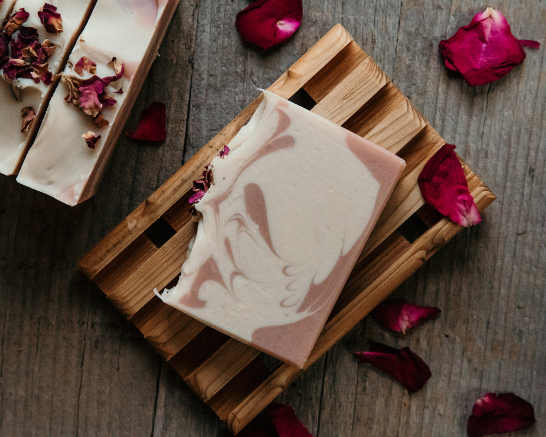 Crooked Chimney Farm Wild Rose Goat Milk Soap on wood soap deck with red rose petals. Pink and white soap. 