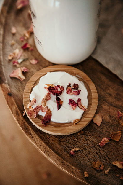 wild rose lotion spread on wood dish with red rose petals. 